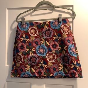 Woven mini skirt with floral pattern. Burgundy base color with colorful flowers.